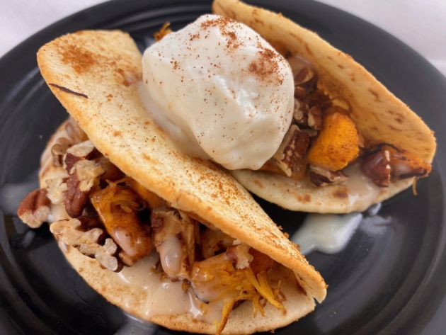 Two vegan pumpkin spice dessert tacos topped with a scoop of non dairy ice cream.