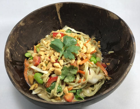 Coconut bowl filled with noodles in a peanut sauce